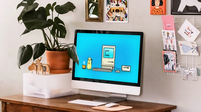 Schreibtisch mit Rechner, auf dem das GMF Wallpaper November zu sehen ist.