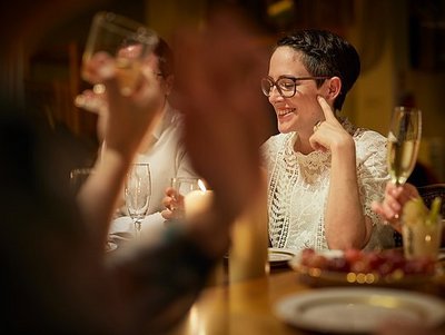 Eine junge Frau sitzt lächelnd mit Freunden an einem Tisch.