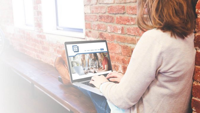 Frau sitzt relaxt auf Bank und schaut sich StuP Digital Website auf dem Laptop an